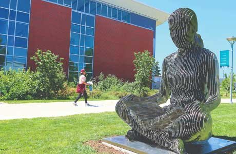 large sculpture of seated person and brick and glass building